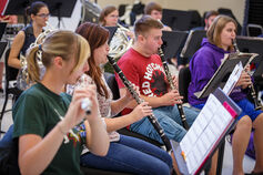 Students in rehearsal playing wind instruments.